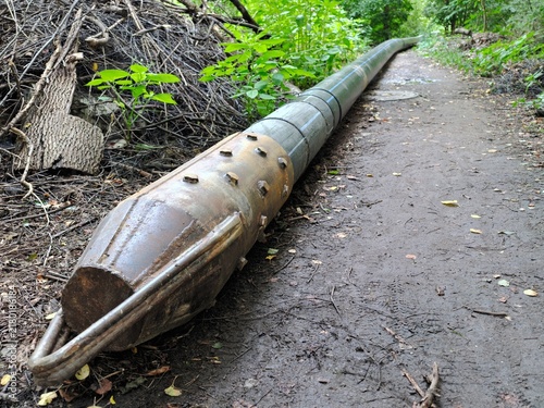 Fotografie Heavy metal core barrel drill pipe resting on a muddy woodland trail