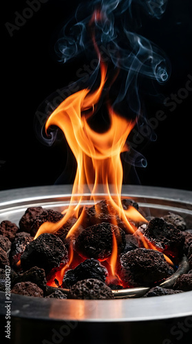 Open Flame Burning on Charcoal in a Metal Fire Pit with Swirling Smoke Against a Dark Background