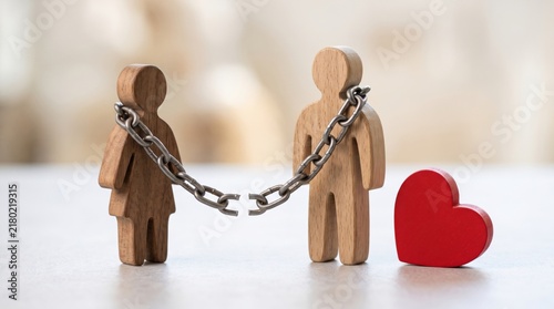 Two wooden figures linked by a broken chain with a red heart beside them, symbolizing broken relationships or emotional separation.