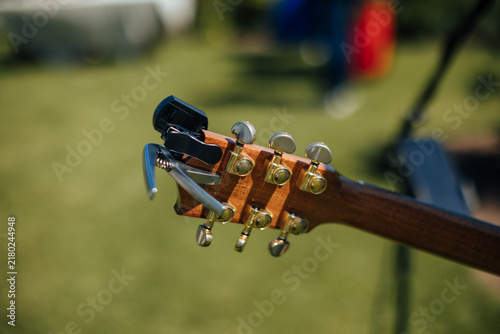 Obraz na płótnie Close-up of a wooden acoustic guitar headstock with metal tuning pegs and a capo