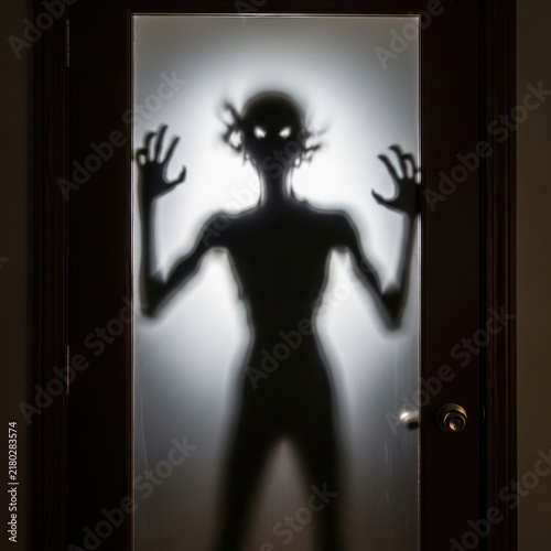 Mysterious shadowy figure reaching out in dark room