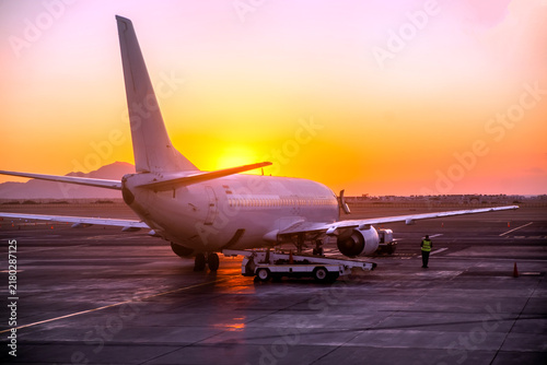 A passenger plane is at the airport at dawn.