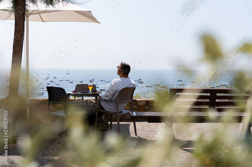 Принти на полотні Man relaxing on terrace, enjoying summer vacation, contemplating tranquil ocean