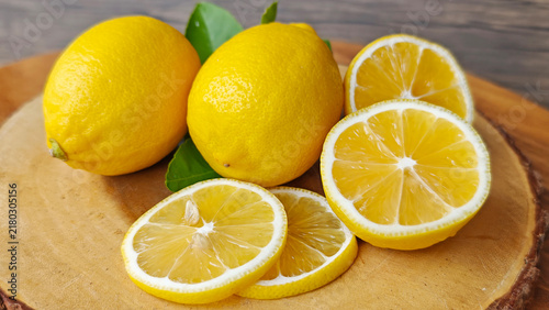Canvas Print Whole and sliced yellow lemons on wooden board.