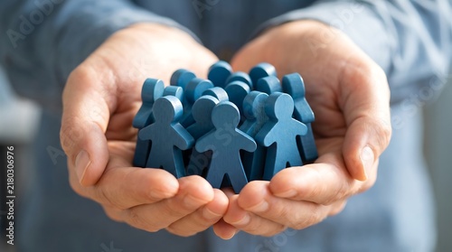 Hands holding group of small blue wooden human figures representing team unity and corporate leadership concept in business management strategy sessions for professional team building success