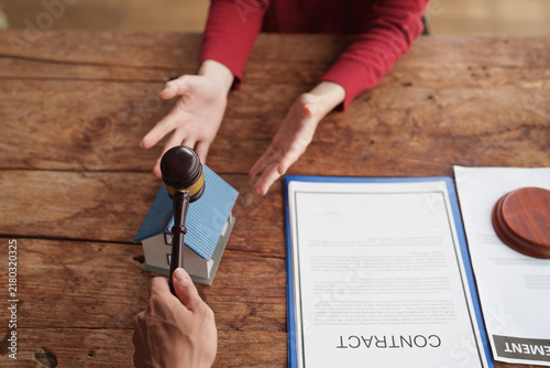 Konstfotografi Gavel hitting a model house with a contract document representing real estate pr