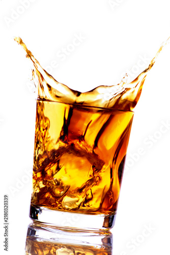 Ice cube falling into whiskey glass