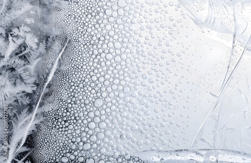tiny air bubbles naturally trapped beneath a translucent sheet of clear ice, clusters of bubbles and delicate frost formations with generous copy space
