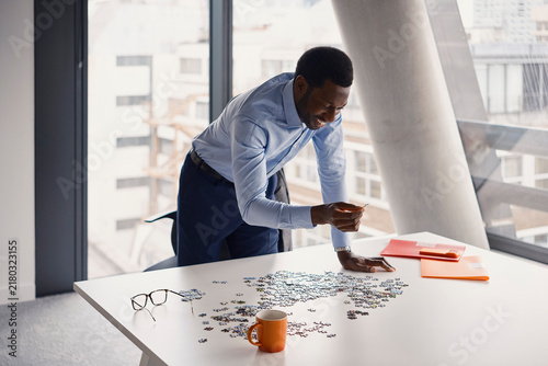 Businessman solves a jigsaw puzzle on a table in a London office