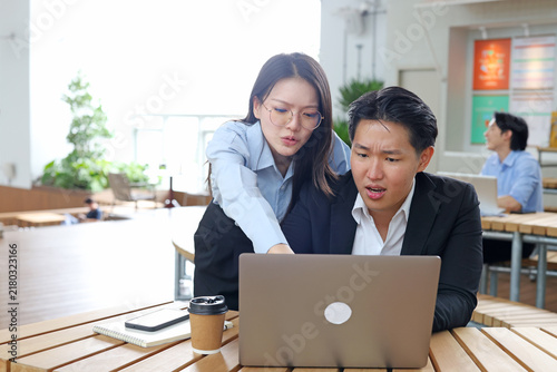 Two Concerned Business Professionals Looking at Laptop Screen in Modern Office
