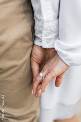 Gentle touch and holding hands of newly married couple outdoors.