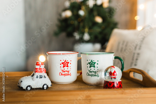 Cozy Christmas morning breakfast tray with festive mugs and holiday decorations in bedroom.