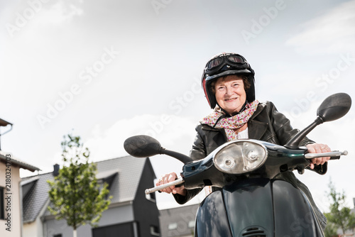 Active senior lady riding motor scooter in the city