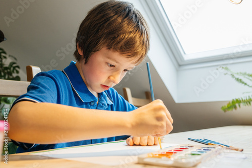 Young boy concentrating on painting watercolor art