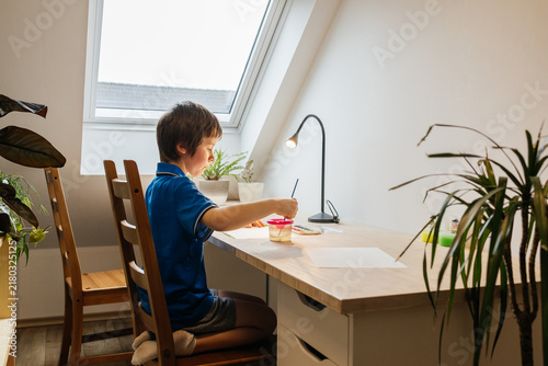Boy concentrating on painting with watercolors at home desk