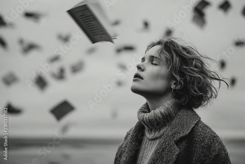 Woman standing amidst falling books on a serene beach during a cloudy day, embodying the essence of dreams and knowledge in a whimsical moment of contemplation