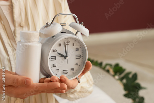 Принти на полотні Woman with alarm clock and pill bottle in bedroom, closeup