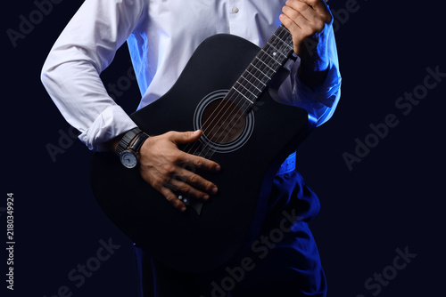 Fotografía Young man with guitar on black background