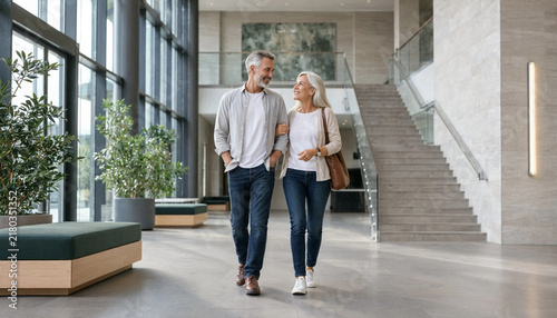 Senior couple walking arm in arm through modern hotel lobby enjoying companionship and retirement lifestyle