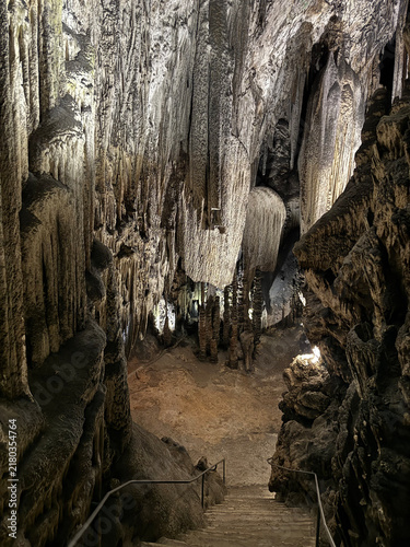 Wide chamber inside the Coves d'Artà, in Capdepera, on the island of Mallorca, Balearic Islands, Spain, with a walkway leading past tall stalagmite columns beneath the cave ceiling.