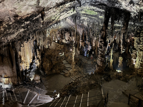 Large cavern inside the Coves d'Artà, in Capdepera, on the island of Mallorca, Balearic Islands, Spain, showing a stone staircase descending through the chamber beneath dense stalactite formations.