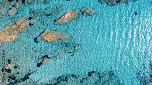 Vue aérienne tournante sur des eaux turquoises transparentes avec des rochers émergeants de l'eau