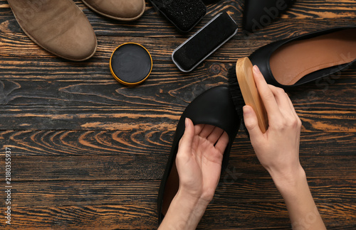 Foto Hands cleaning shoes with brush on wooden background