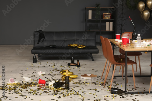 Interior of messy office with couch and table after New Year party