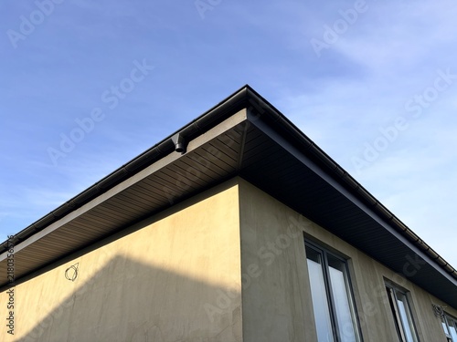 A view of a house under construction with a finished roof at sunset
