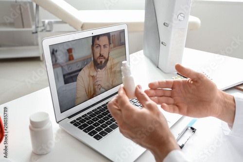 Male doctor showing drops to patient online in office, closeup