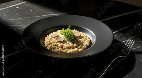 Truffle Risotto Elegance: A gourmet dish of truffle risotto, garnished with fresh herbs and thinly sliced truffle, served in a sophisticated black bowl on a dark marble surface.