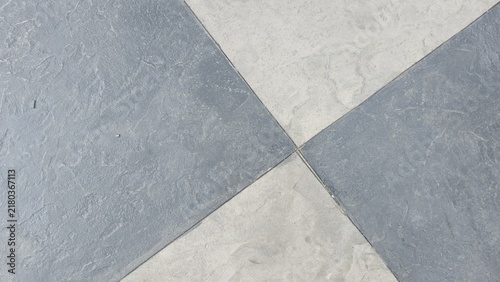 Stamped concrete floor with grey and black checkerboard pattern. Top view of a checkered stamped concrete patio floor with textured stone finish. Modern geometric paver texture background.