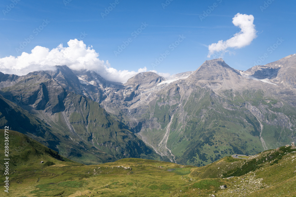 Obraz premium Panoramic View of Alpine Mountains with Green Valleys under Blue Sky on a Sunny Day