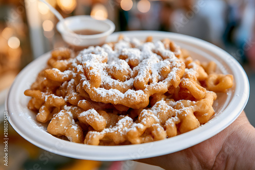 Delicious Funnel Cake Served at Fair with Powdered Sugar Dusting and Syrup on Side in Hand-Held Plate