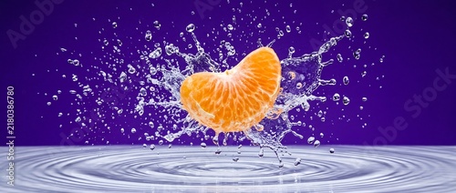 Ripe orange slice falling into water surface causing circular ripples and spray against purple background for vibrant fruit advertising and healthy food campaign.