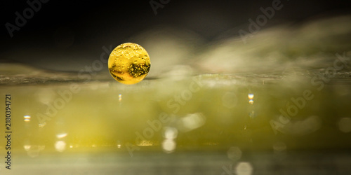 Konstfotografi Golden oil drop bubble suspended in water