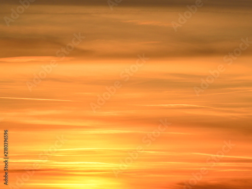 Fotografie A sky covered with altostratus clouds reflecting the golden light of the setting sun at the end of an  autumn day