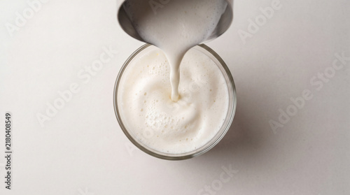Barista pouring frothed milk into glass cup top view