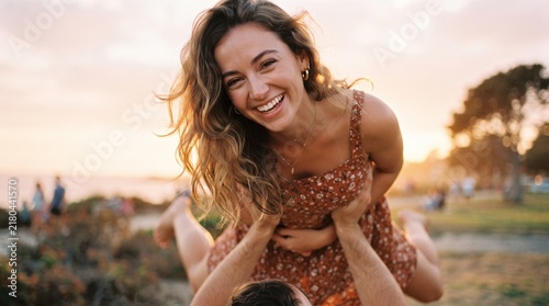 Happy woman laughing joyfully while holding child outdoors at sunset