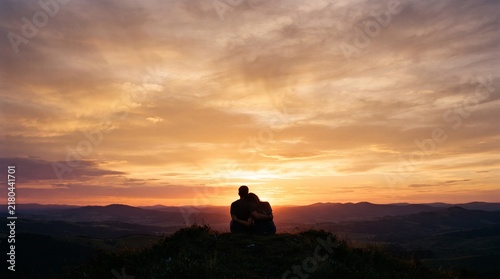 Silhouette of person meditating at sunset overlooking vast horizon and mountains