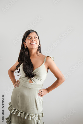 Woman in green dress with hands on hips looking up and smiling
