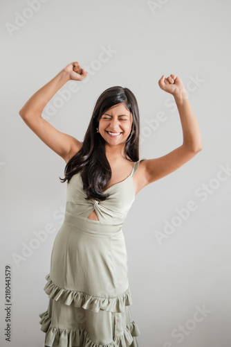 Woman in green dress celebrating with arms raised