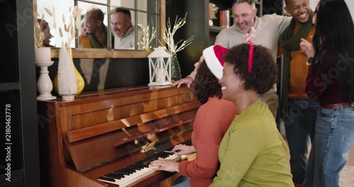 Diverse group gathering at upright piano home, pianist starting song in Santa hat for holiday carol
