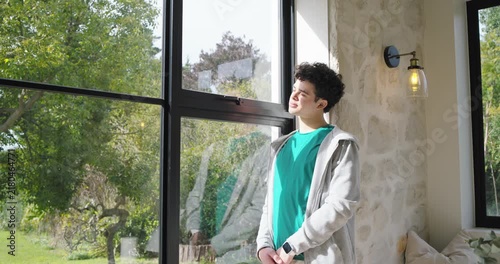 African American man standing by black window tilting head as sunlight hits face smiling