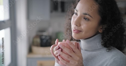 African American woman at kitchen window holding pink mug savoring aroma glancing to camera smiling