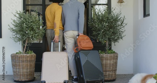 Pause ending as two adults are pushing open front door walking inside pulling suitcases going home