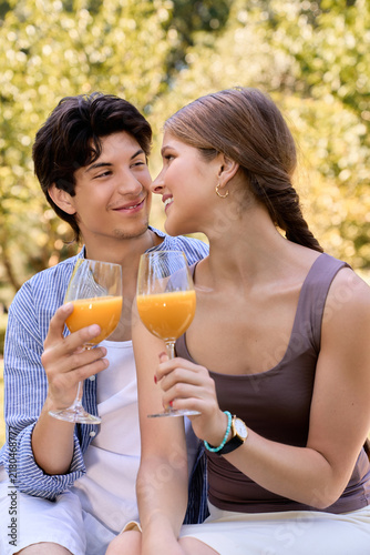 Foto A happy couple sits closely together sharing drinks, surrounded by trees and gre