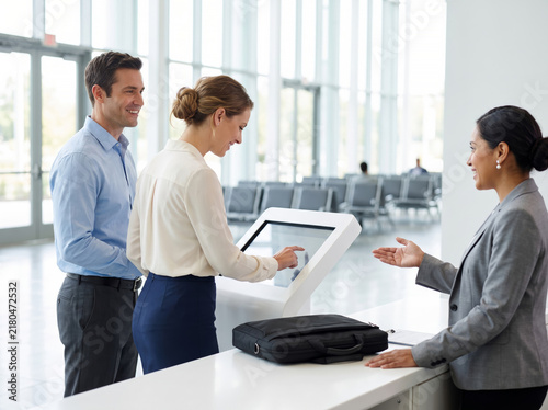 Colleagues checking in at a conference registration kiosk with staff, representing seamless corporate events and premium networking.