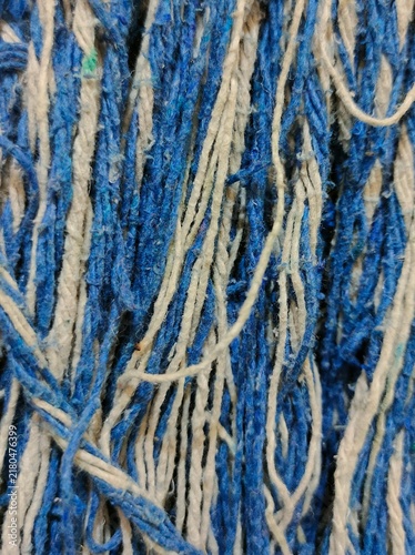 A close-up of the tightly woven, worn mop fiber strands, colored blue-grey, creating a textured vertical pattern