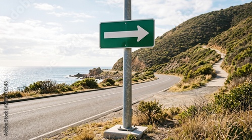 Green evacuation route directional sign pointing inland on coastal highway depicting tsunami safety and emergency preparedness